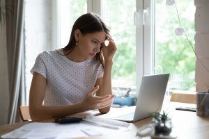 woman confused at desk with laptop