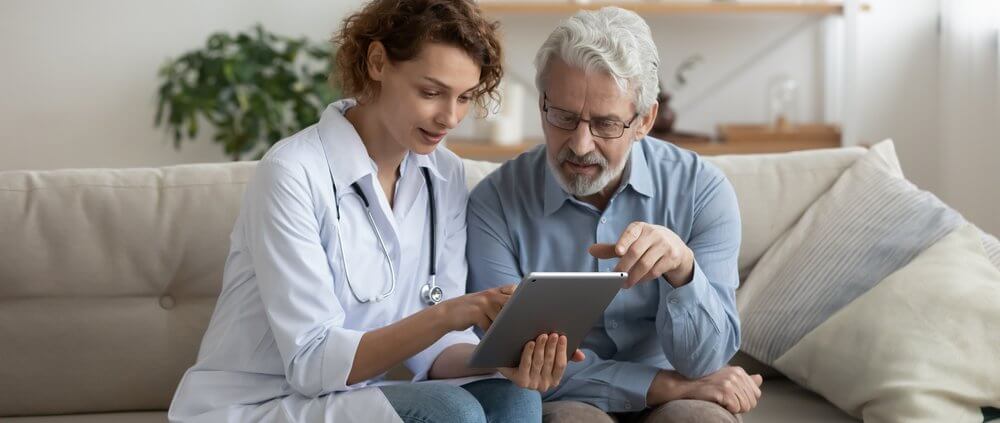 woman doctor and elderly man looking at a tablet