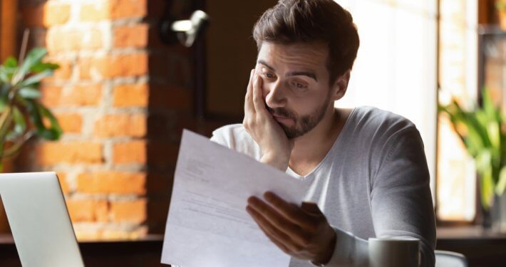 man looking disappointed at a piece of paper