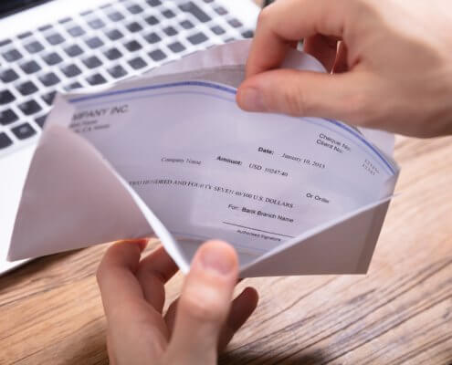 person opening an envelope with a check inside