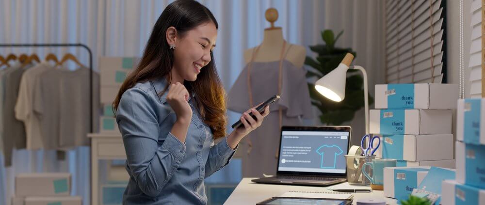 small business owner looking at her phone excitedly
