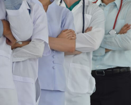 several healthcare workers lined up in a row with their arms crossed