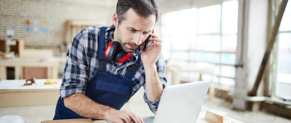man looking confused while starting at a laptop in a workshop