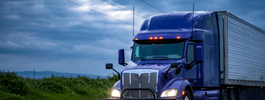 blue semi truck driving at dusk