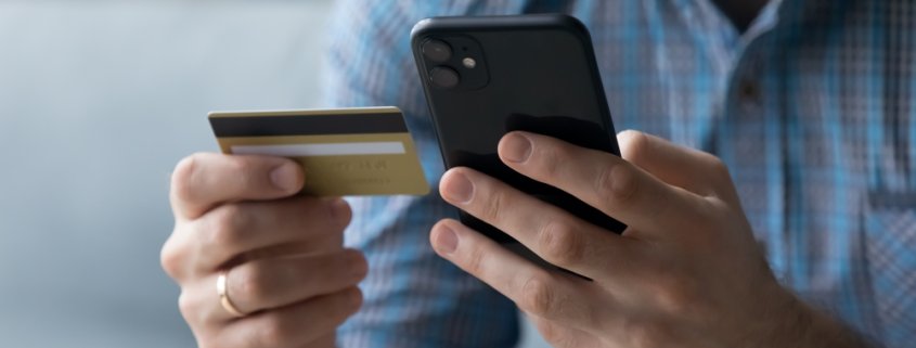 person holding a credit card and typing on a smart phone