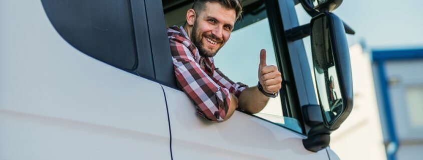 trucker in a semi-truck giving a thumbs up