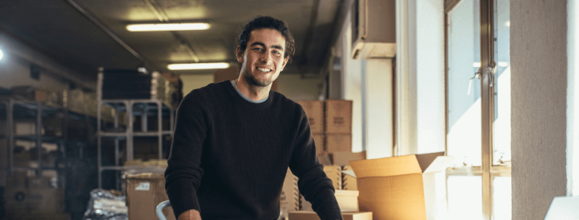 male small business owner smiling while packing an order