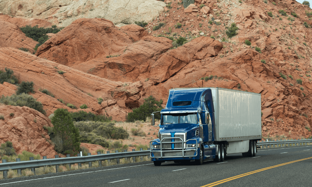 blue and white semi truck driving past mountains