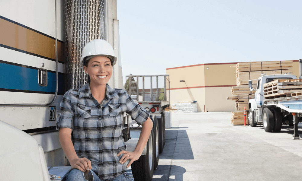 female trucker standing next to truck and smiling