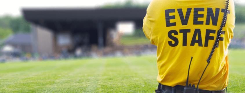 person wearing a yellow "event staff" shirt watching the event