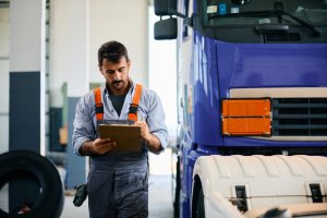 man with clip board in front of semi truck