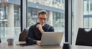 business man smiling while looking at laptop on his desk